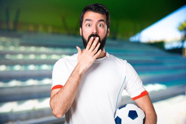 Bir futbol sahası üzerinde bir futbol topu yapma sürpriz jest sahip futbol oyuncu