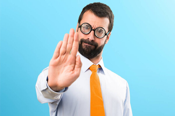 Смешной человек в очках делает знак стоп на красочном фоне
