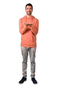 Adam tam vücut kopya alanı izole beyaz zemin üzerinde bir reklam eklemek için avuç hayali tutan bir pembe kazak içinde