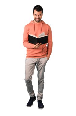 Adam tam vücut içinde pembe bir kazak bir kitap ve izole beyaz arka plan üzerinde okuma zevk