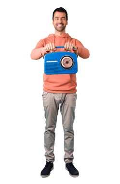 Adam tam vücut içinde mavi bir vintage radyo izole beyaz arka plan üzerinde tutan bir pembe kazak