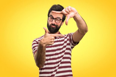 Onun parmaklarıyla renkli arka plan üzerinde odaklanan gözlüklü adam