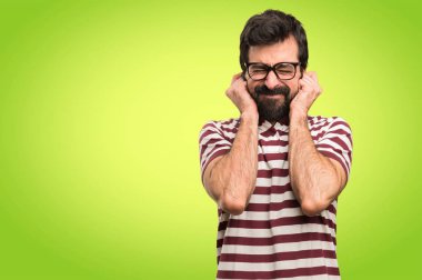 Kulakları renkli arka plan üzerinde kapsayan gözlüklü adam