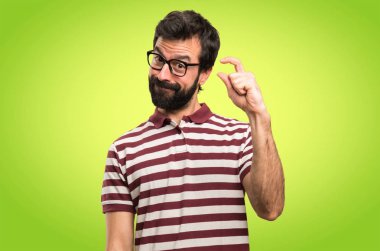 Küçük işareti renkli arka plan üzerinde yapma gözlüklü adam