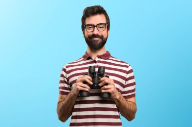 Renkli arka plan üzerinde dürbün ile gözlüklü mutlu adam