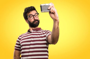 Renkli arka plan üzerinde bir kamera tutarak gözlüklü adam