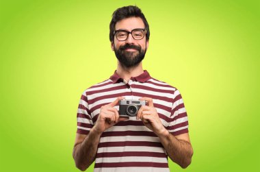Gözlüklü bir kamera renkli arka plan üzerinde tutarak mutlu adam