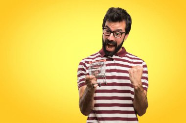 Renkli arka plan üzerinde tutmak bir süpermarket arabası oyuncak gözlüklü adam