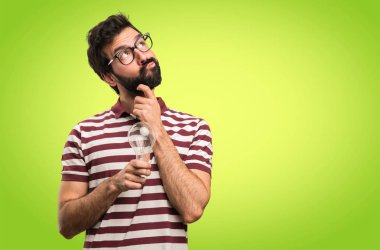 Bir ampul renkli arka plan üzerinde tutarak gözlüklü adam