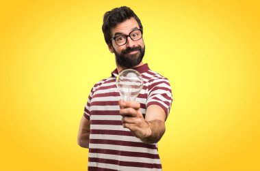 Gözlüklü bir ampul renkli arka plan üzerinde tutan mutlu adam