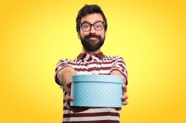 Gözlüklü bir hediye renkli arka plan üzerinde tutan mutlu adam