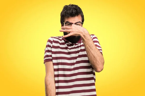 Man with glasses making smelling bad gesture on colorful background