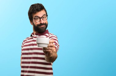 Bir fincan kahve renkli arka plan üzerinde tutarak gözlüklü mutlu adam