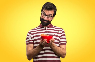 Bir kase tahıl renkli arka plan üzerinde tutarak gözlüklü adam