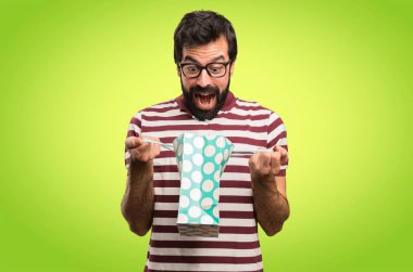 Renkli arka plan üzerinde alışveriş çantası ile gözlüklü şaşırmış adam