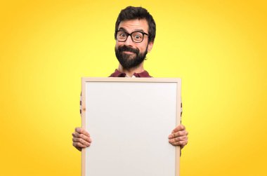Boş bir afişini renkli arka plan üzerinde tutarak gözlüklü mutlu adam