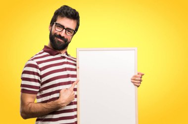 Boş bir afişini renkli arka plan üzerinde tutarak gözlüklü mutlu adam