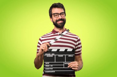 Gözlüklü bir Klaket renkli arka plan üzerinde tutan mutlu adam