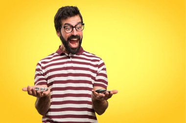 Renkli arka plan üzerinde poker fişleri tutan gözlüklü şaşırmış adam