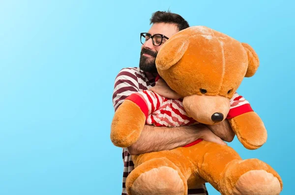 Man with glasses playing with stuffed animal on colorful background