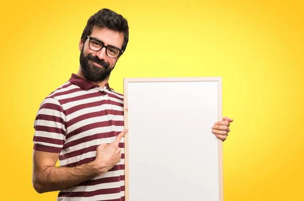 带眼镜的快乐男人在五颜六色的背景上拿着一个空标语牌 — 图库照片