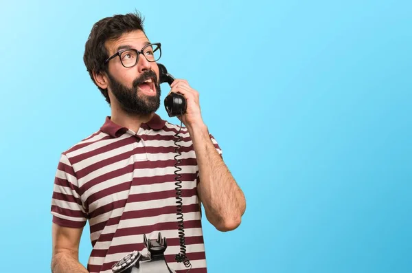 Man with glasses talking to vintage phone on colorful background