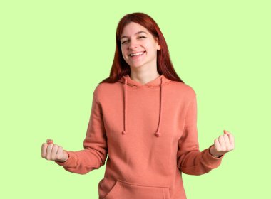 Zafer ve yeşil renkli bir ödül kazandığı için mutlu pembe kazak kutluyor ile genç Kızıl saçlı kız