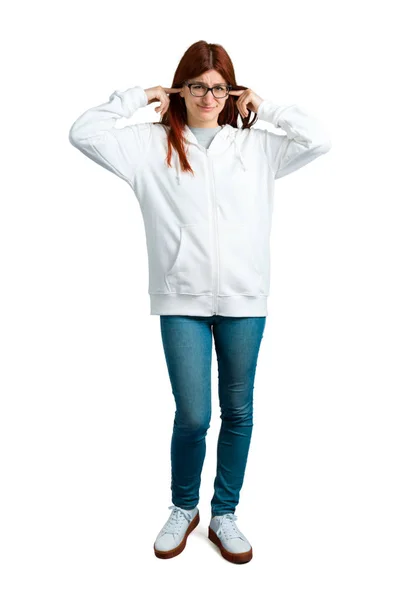 年轻的红头发女孩在城市白色运动衫与眼镜覆盖两个耳朵用手 孤立的白色背景下的沮丧表达式 — 图库照片