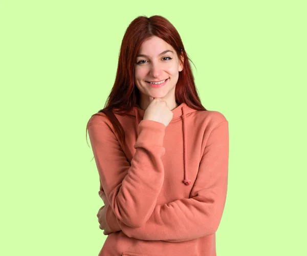 笑顔と自信を持って顔の前面を緑の背景のピンクのトレーナーと若い赤毛の女の子 — ストック写真