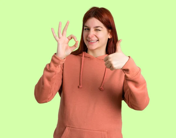 Junge Rothaarige Mädchen Mit Rosa Sweatshirt Zeigt Ein Zeichen Mit — Stockfoto