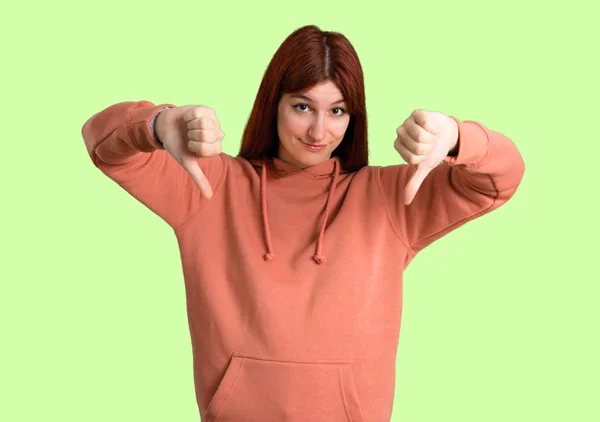 Young Redhead Girl Pink Sweatshirt Showing Thumb Both Hands Negative — Stock Photo, Image