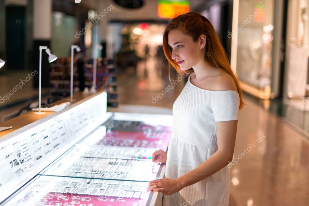 Young redhead pretty girl in a shopping center looking at jewelry