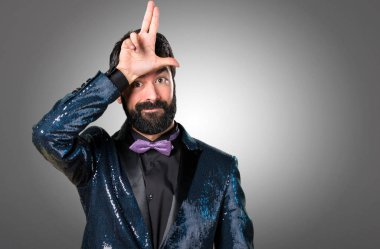 Yakışıklı adam aptal yapma payet ceket gri arka plan üzerinde oturum