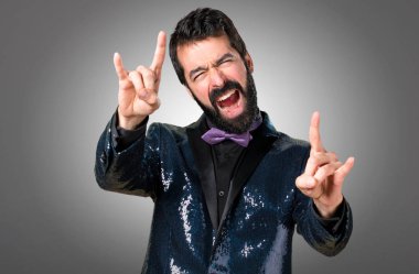 Payet ceket gri arka plan üzerinde yapım boynuz hareketi ile yakışıklı adam