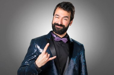 Payet ceket gri arka plan üzerinde yapım boynuz hareketi ile yakışıklı adam