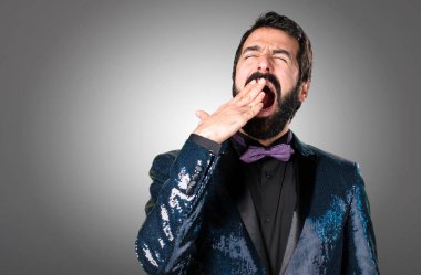 Payet ceket gri arka plan üzerinde esneme ile yakışıklı adam