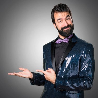 Bir şey gri arka plan üzerinde tutan payet ceket ile yakışıklı adam