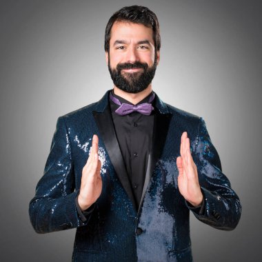 Bir şey gri arka plan üzerinde tutan payet ceket ile yakışıklı adam