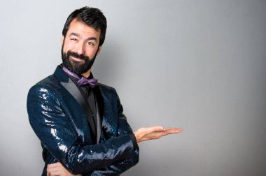 Bir şey gri arka plan üzerinde sunulması payet ceket ile yakışıklı adam