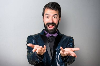 Bir şey gri arka plan üzerinde sunulması payet ceket ile yakışıklı adam