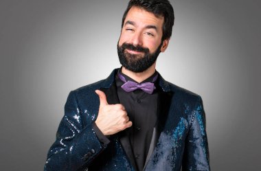 Payet ceket gri arka plan üzerinde başparmak ile yakışıklı adam