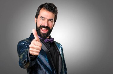 Payet ceket gri arka plan üzerinde başparmak ile yakışıklı adam