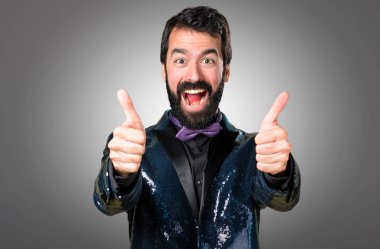 Payet ceket gri arka plan üzerinde başparmak ile yakışıklı adam