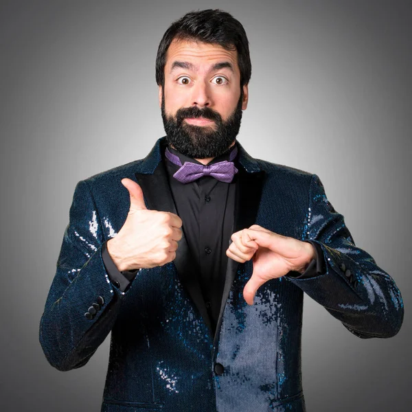 İyi-kötü işareti gri arka plan üzerinde yapma payet ceket ile yakışıklı adam