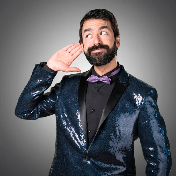 Payet ceket gri arka plan üzerine bir şey dinleme ile yakışıklı adam