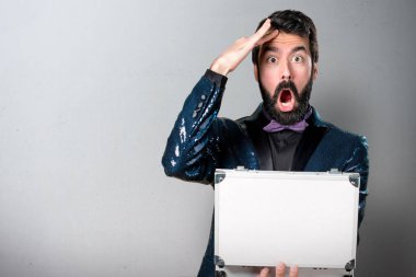 Bir evrak çantası gri arka plan üzerinde tutarak payet ceket ile yakışıklı adam