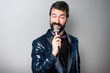Yakışıklı adam payet ceket şarkı gri arka plan üzerinde mikrofon ile