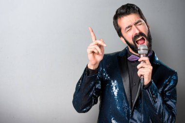 Yakışıklı adam payet ceket şarkı gri arka plan üzerinde mikrofon ile