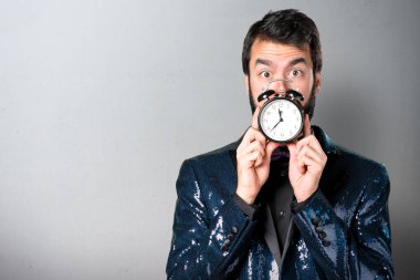Vintage saat gri arka plan üzerinde tutarak payet ceket ile yakışıklı adam