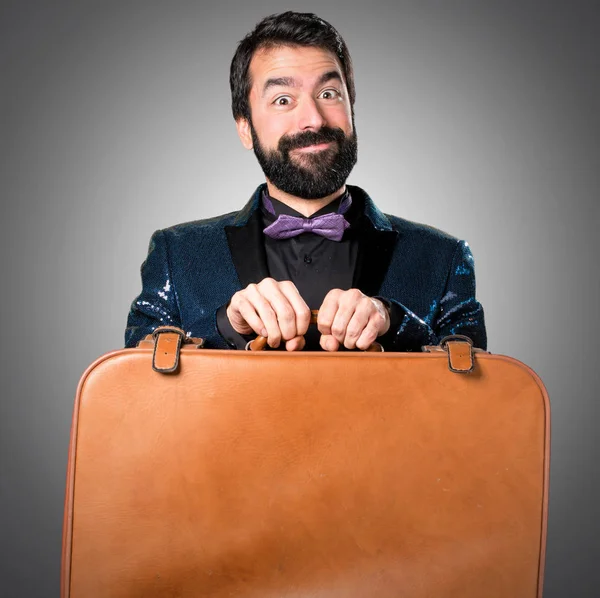 Yakışıklı bir vintage çanta gri arka plan üzerinde tutarak payet ceket ile